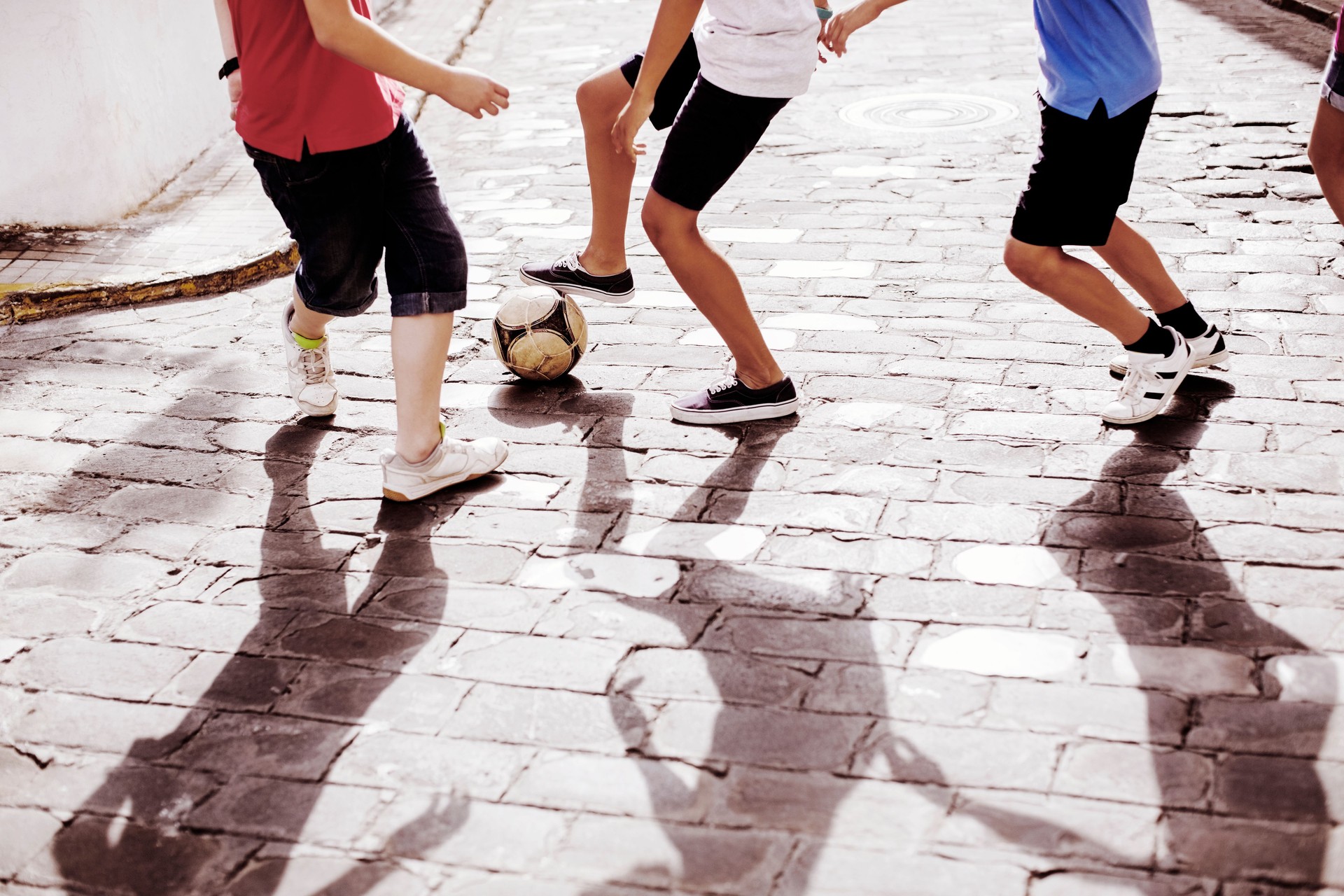 Children playing with soccer ball in alley